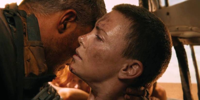 Max, played by Tom Hardy, holds an injured Furiosa, played by Charlize Theron, up so she can whisper to him in Mad Max: Fury Road