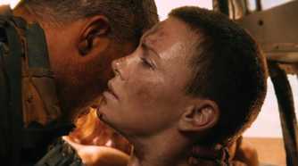 Max, played by Tom Hardy, holds an injured Furiosa, played by Charlize Theron, up so she can whisper to him in Mad Max: Fury Road