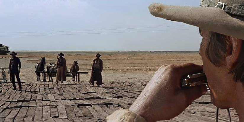 Harmonica (Charles Bronson) plays in front of the three gunmen at the train station in 'Once Upon a Time in the West'