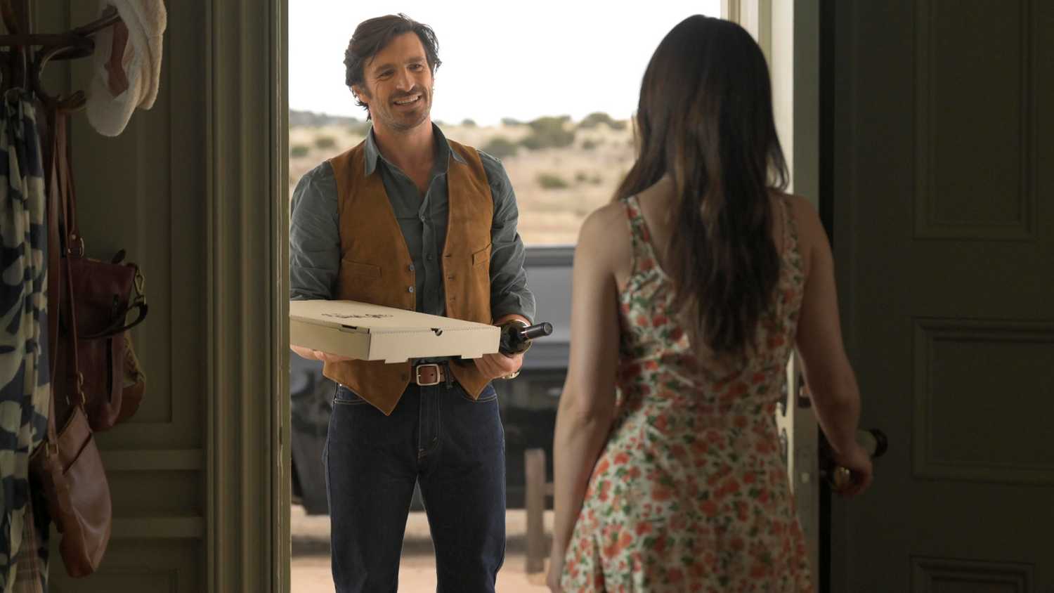 Eoin Macken as Davis Collins standing at the door of Minka Kelly as Quinn with a pizza in Ransom Canyon
