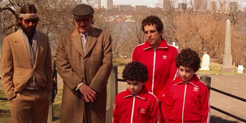 Luke Wilson, Gene Hackman, and Ben Stiller as Richie, Royal, and Chas wearing brown suits and a red jumpsuit standing in a graveyard in 'The Royal Tenenbaums'