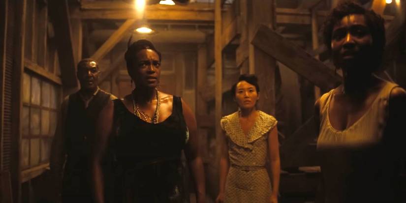 Annie (Wunmi Mosaku) and Grace (Li Jun Li) stand in a group and look fearful in Sinners.