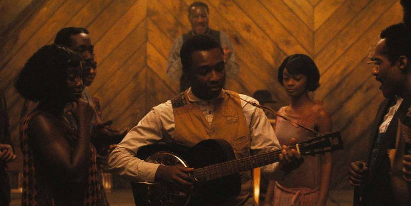 Miles Caton playing a musical instrument as other people look on in Ryan Coogler's Sinners.