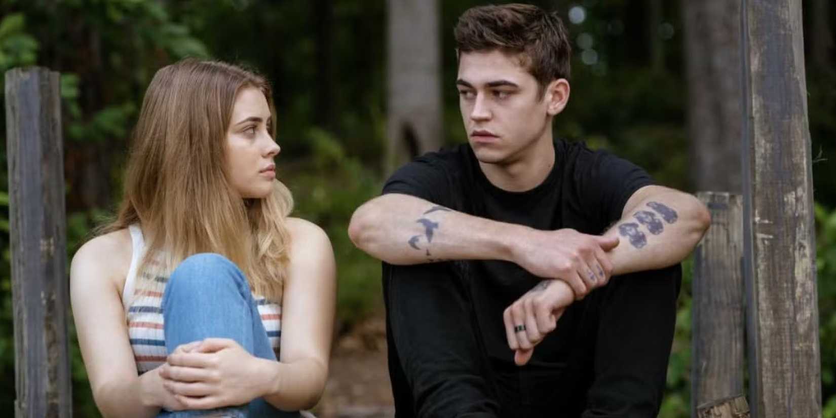 Josephine Langford ve Hero Fiennes Tiffin yan yana oturuyor ve sonra birbirlerine bakıyor