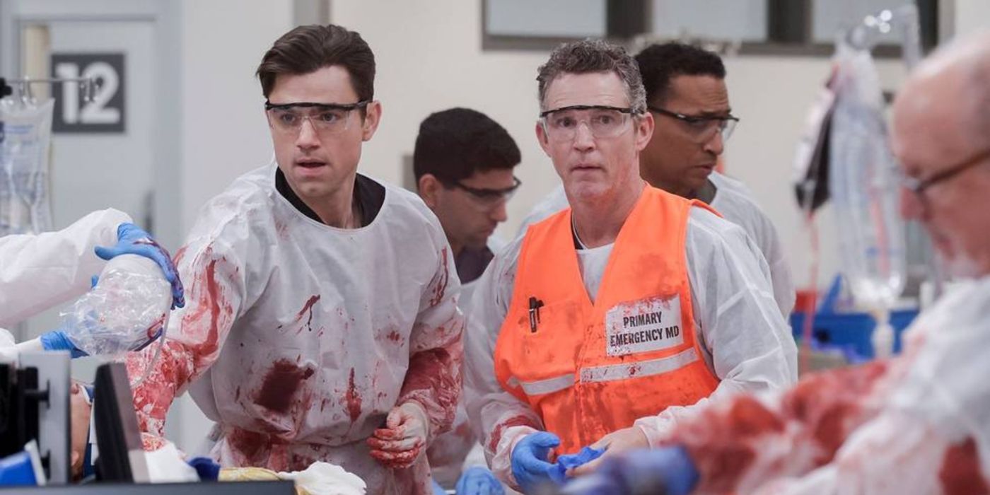 Langdon (Patrick Ball) and Abbot (Shawn Hatosy) standing next to each other wearing goggles and scrubs in The Pitt.
