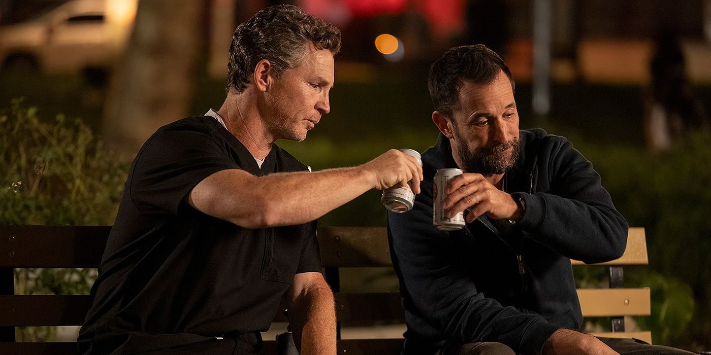 Shawn Hatosy as Dr. Abbot and Noah Wyle as Dr. Robby clinking beer cans in a park in The Pitt Season 1, Episode 15.