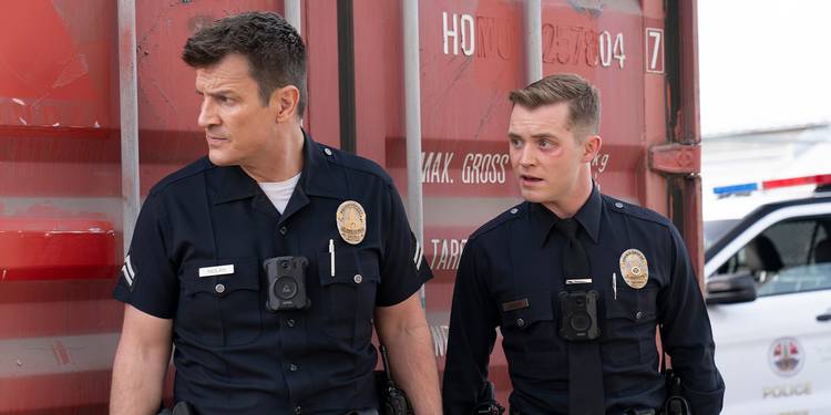Nathan Fillion and another uniformed officer hide behind a shipping container on The Rookie