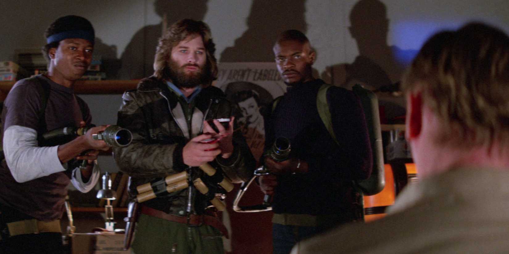 Kurt Russell and two costars stare uneasily at another man in The Thing.