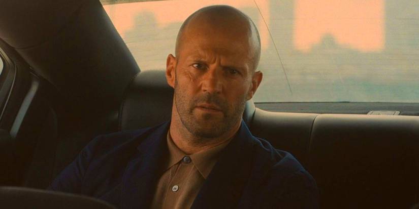 Jason Statham sitting in the backseat of a car in Wrath of Man