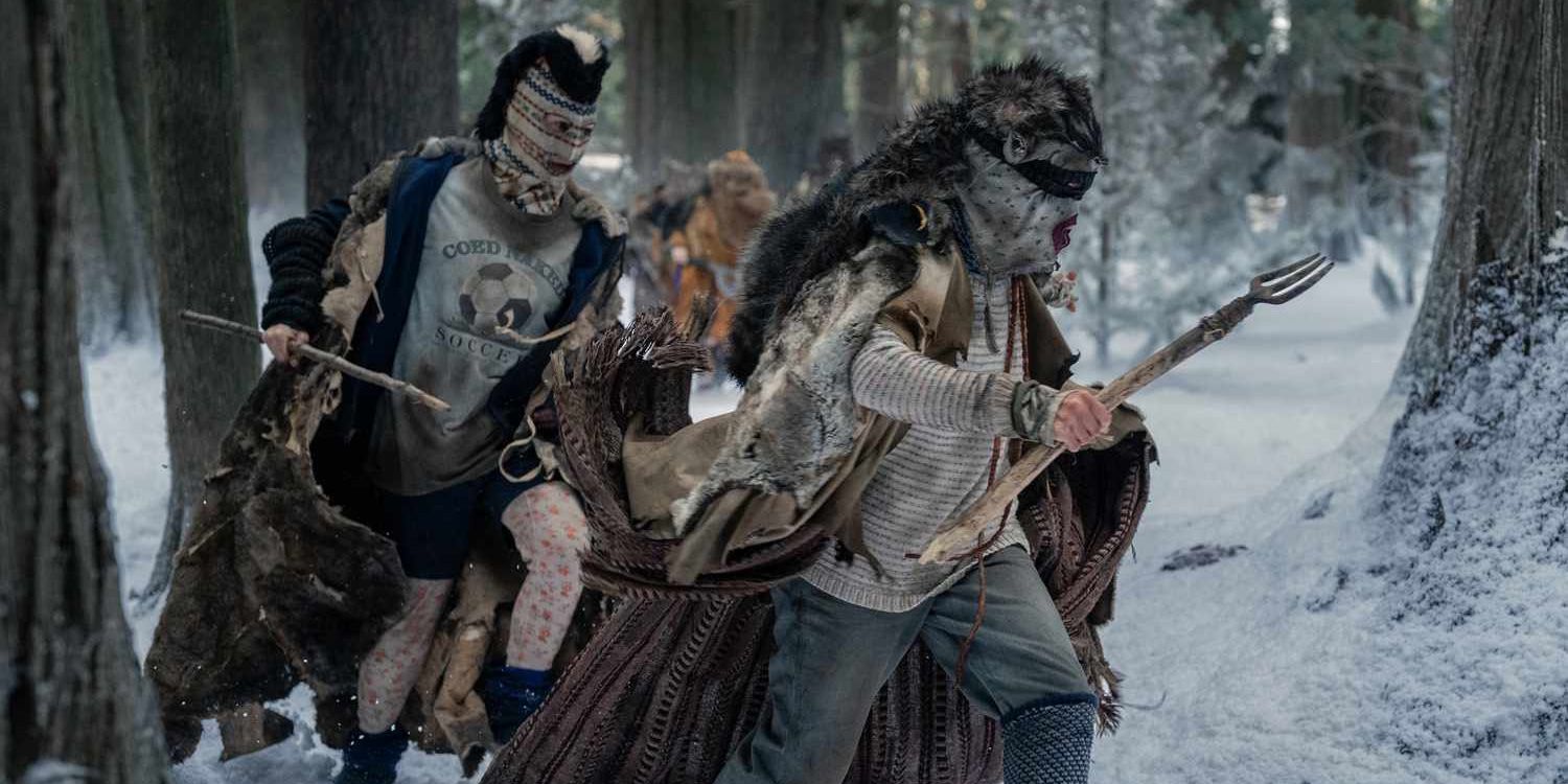 The Yellowjackets, dressed in mismatched winter clothing and masks, holding weapons while running through the snowy woods in the Season 3 finale