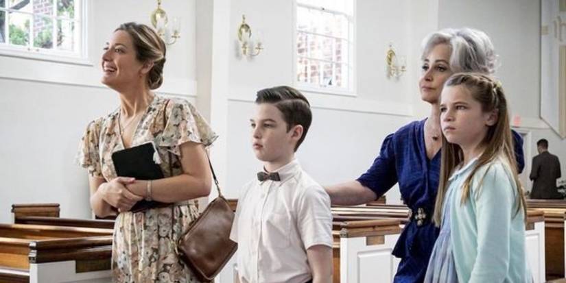 Sheldon and his family in the isle of a church with empty pews, looking off-camera in Young Sheldon.