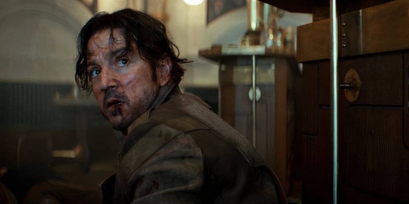 Cassian Andor (Diego Luna), his face bloody, looking up at an offscreen Syril Karn in Andor
