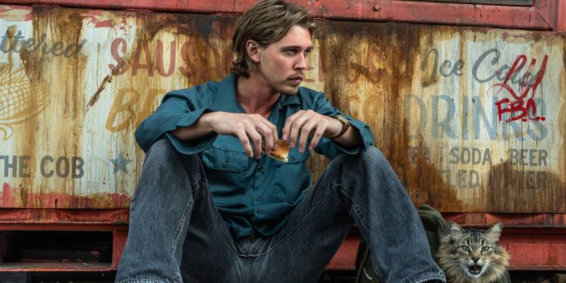 Austin Butler as Hank, leaning against a dumpster next to Bud the cat in Caught Stealing.