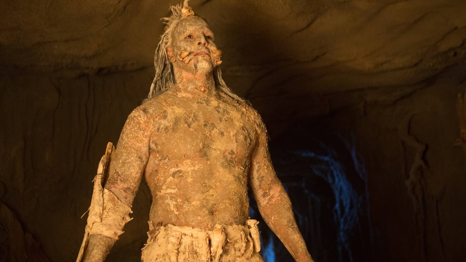 The villain in Bone Tomahawk (2015) standing in a dimly-lit cave and looking menacing