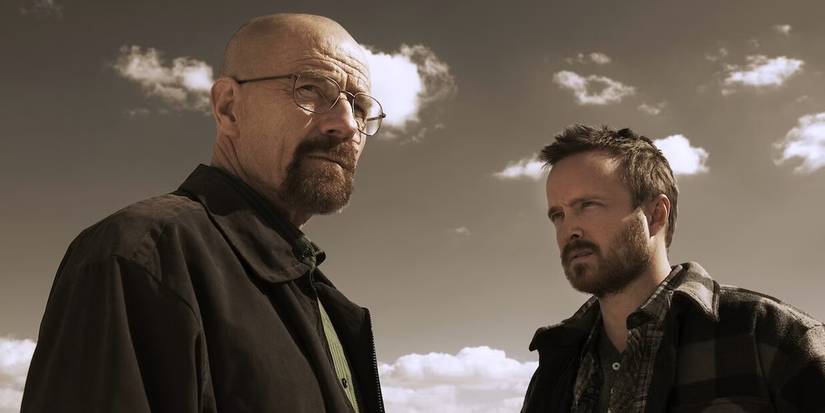 Bryan Cranston and Aaron Paul stare into the distance against a dull sky in Breaking Bad.