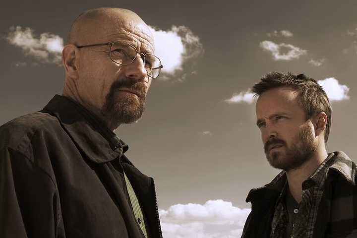 Bryan Cranston and Aaron Paul stare into the distance against a dull sky in Breaking Bad.