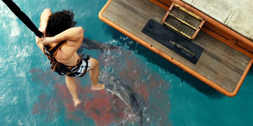 Josh Heuston dangling from a rope below bloody water in Dangerous Animals