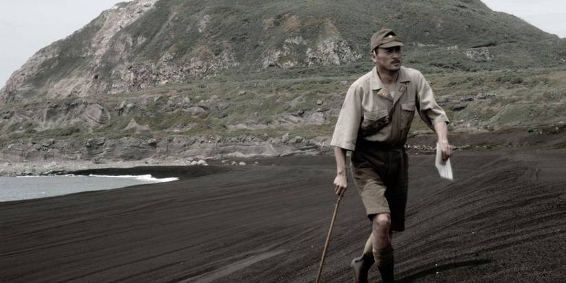A soldier holds a letter in his hand and walks along a beach with a cane in Letters from Iwo Jima.