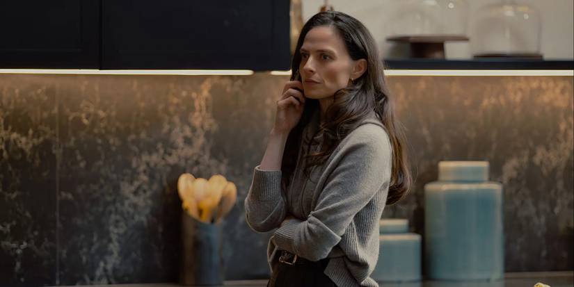 Bella (Lara Pulver) standing near a counter with a hand raised to her face in MobLand
