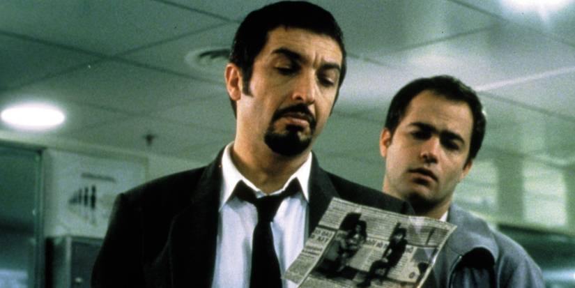 Two men looking at a newspaper cut in Nine Queens