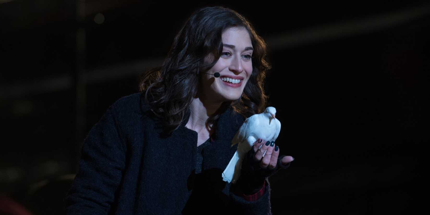 Lizzy Caplan as Lula holding a white dove on stage in Now You See Me 2.