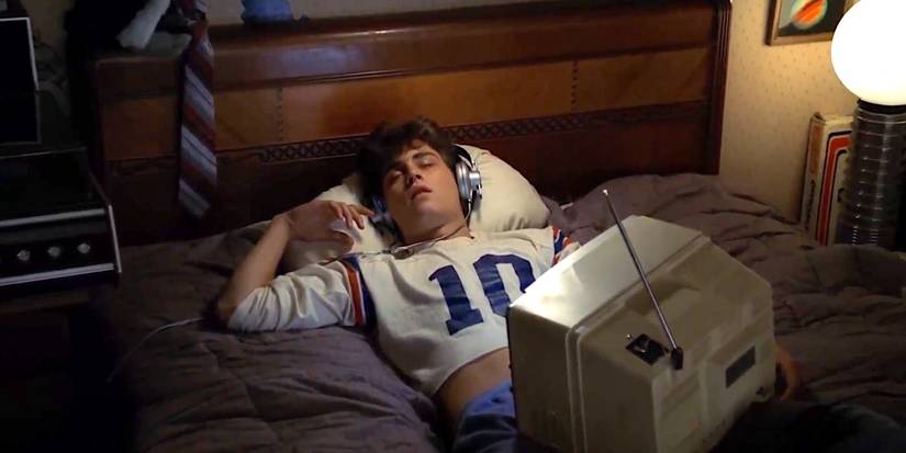 Glen (Johnny Depp) asleep on his bed, wearing headphones and with a television perched on his lap in A Nightmare on Elm Street (1984).