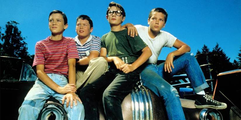 Wil Wheaton, Jerry O'Connell, Cory Feldman, and River Phoenix sitting on a car in Stand by Me.