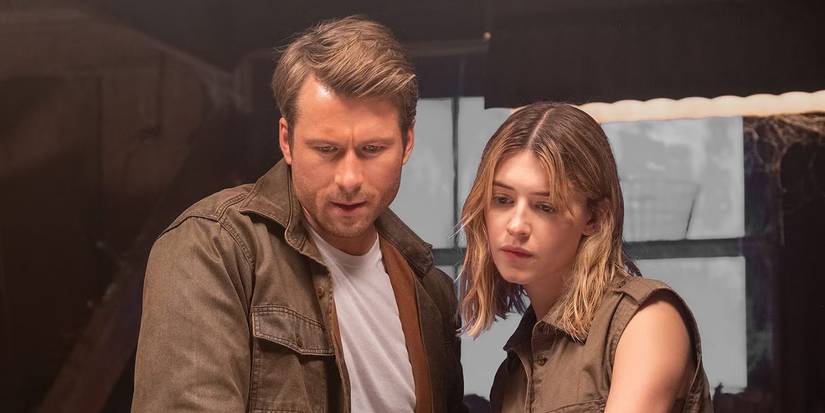 Glen Powell and Daisy Edgar Jones looking at something on a table in Twisters, 2024.