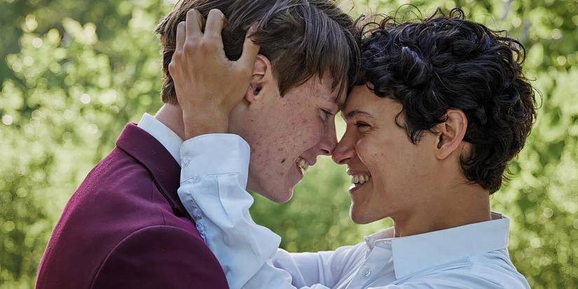 Young Royals' Wilhelm and Simon holding each other tenderly while smiling. 