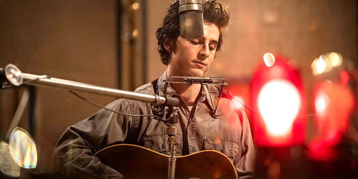 Timothée Chalamet strumming a guitar as Bob Dylan in A Complete Unknown.