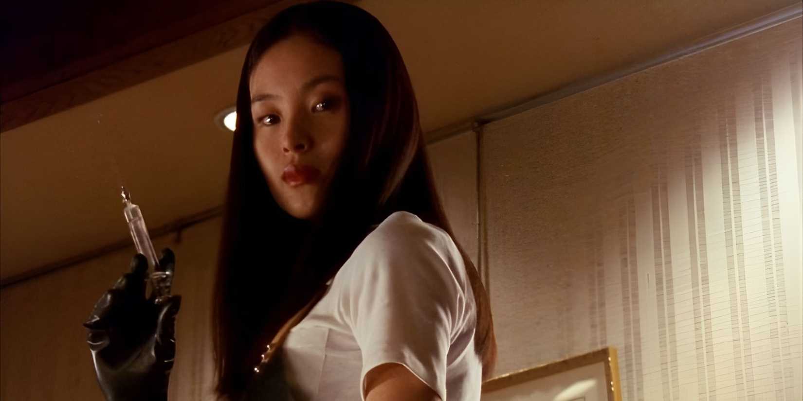 A woman holds a needle and looks to the side with an ominous expression in Audition.