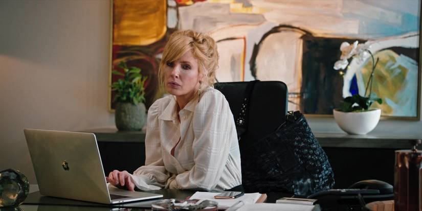 Beth sits at her desk using her laptop and looking to the distance in Yellowstone episode Resurrection Day.