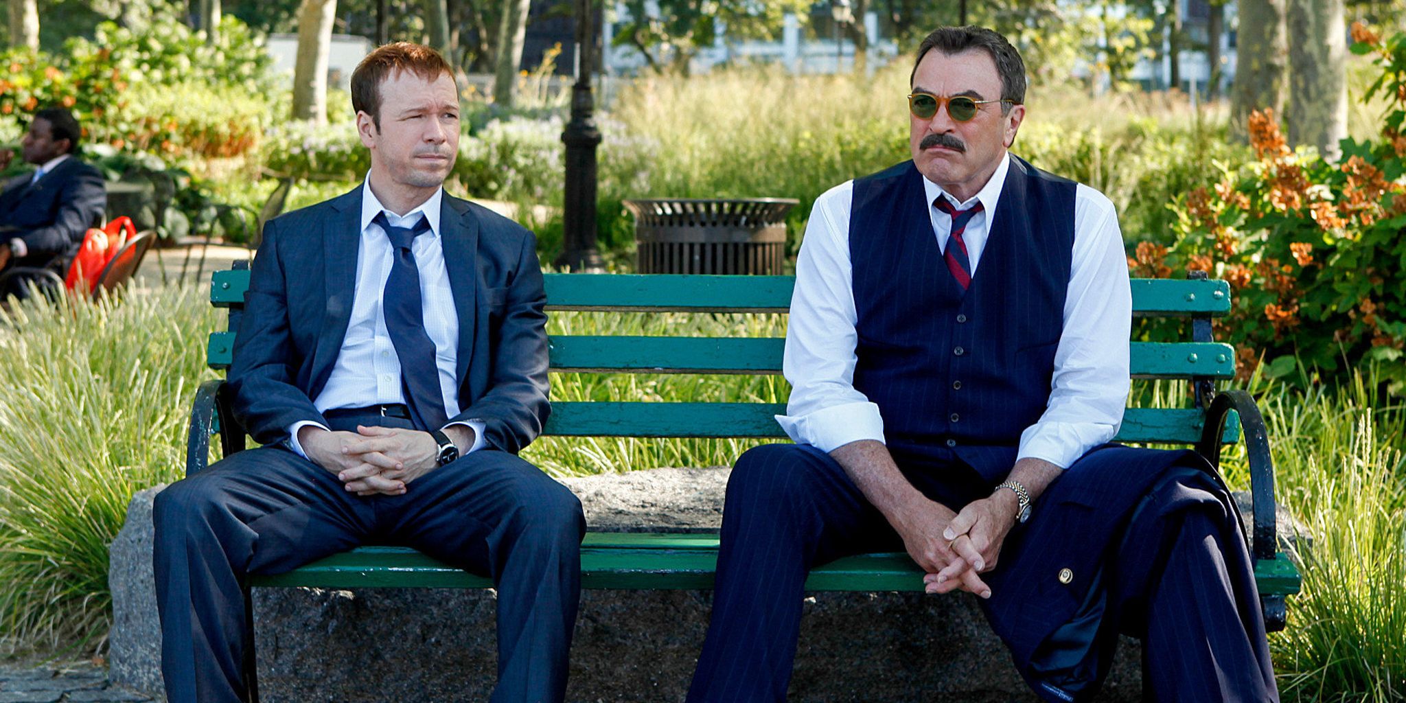 Donnie Wahlberg and Tom Selleck sit on a bench in Blue Bloods