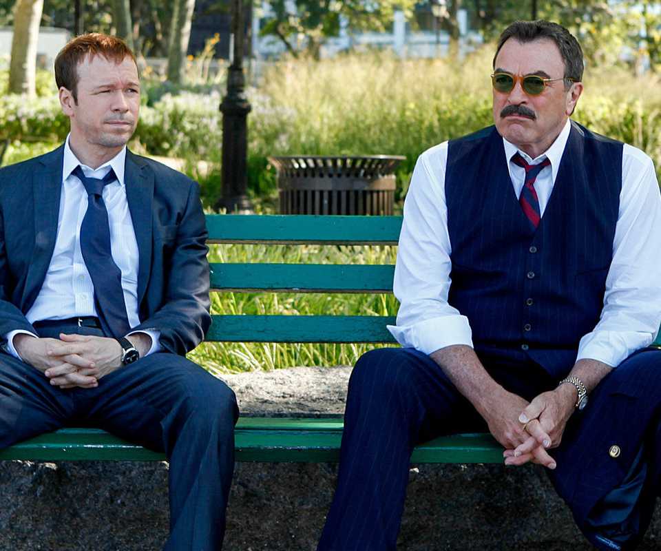 Donnie Wahlberg and Tom Selleck sit on a bench in Blue Bloods