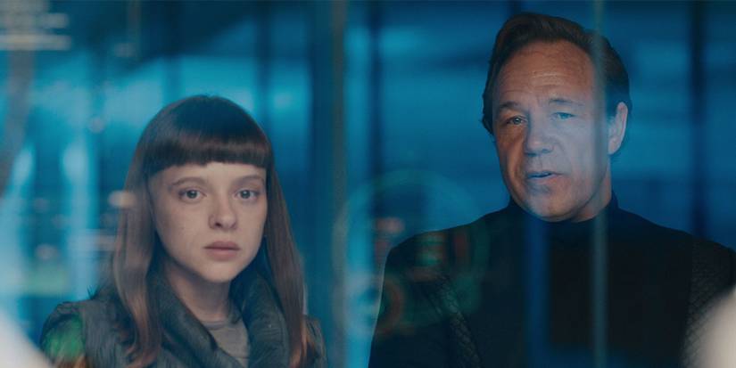 A woman and man look through a glass window in Bodies.