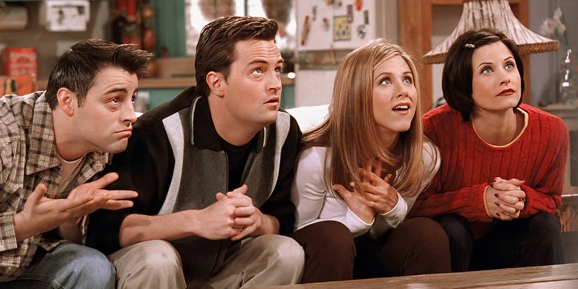 The cast of Friends on a couch looking up at a TV
