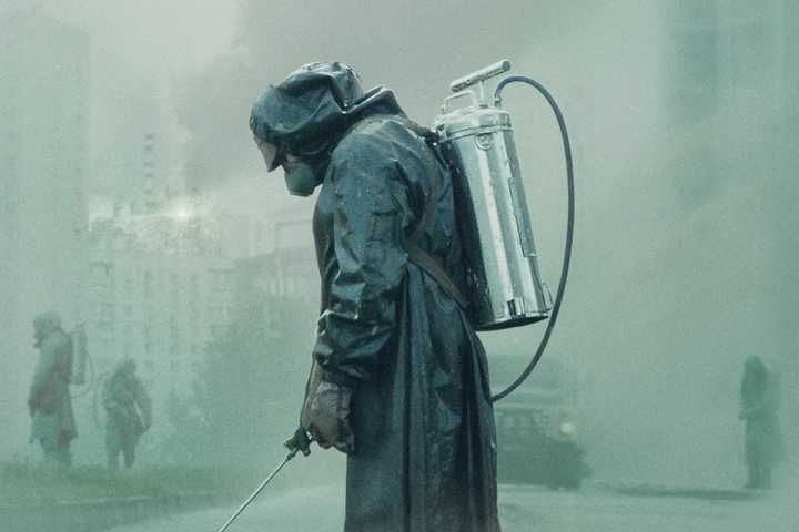 Person in a radioactive suit spraying a chemical in a foggy background in 'Chernobyl.'