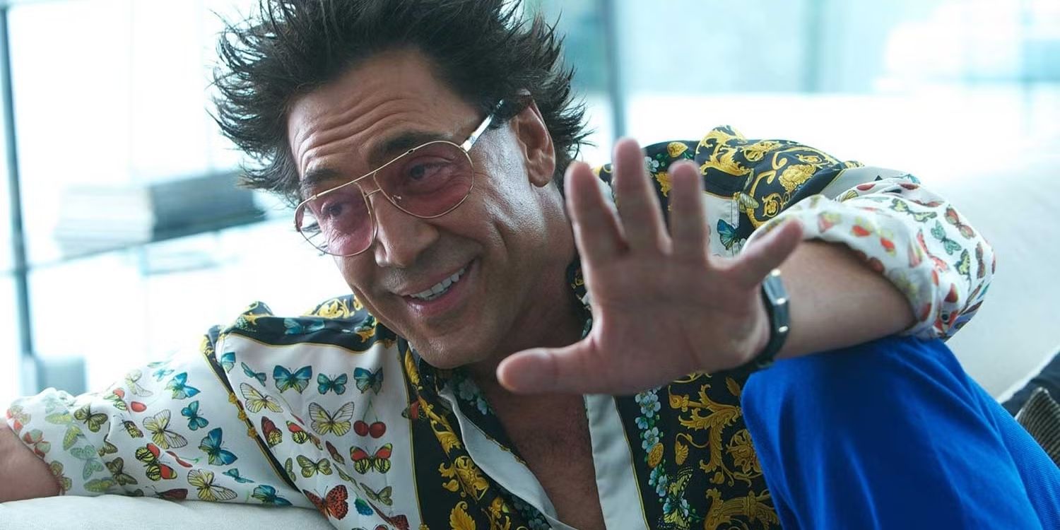 Actor Javier Bardem as Reiner, with sunglasses, spiked hair and a bright shirt, holding out his hand and smiling in The Counselor.