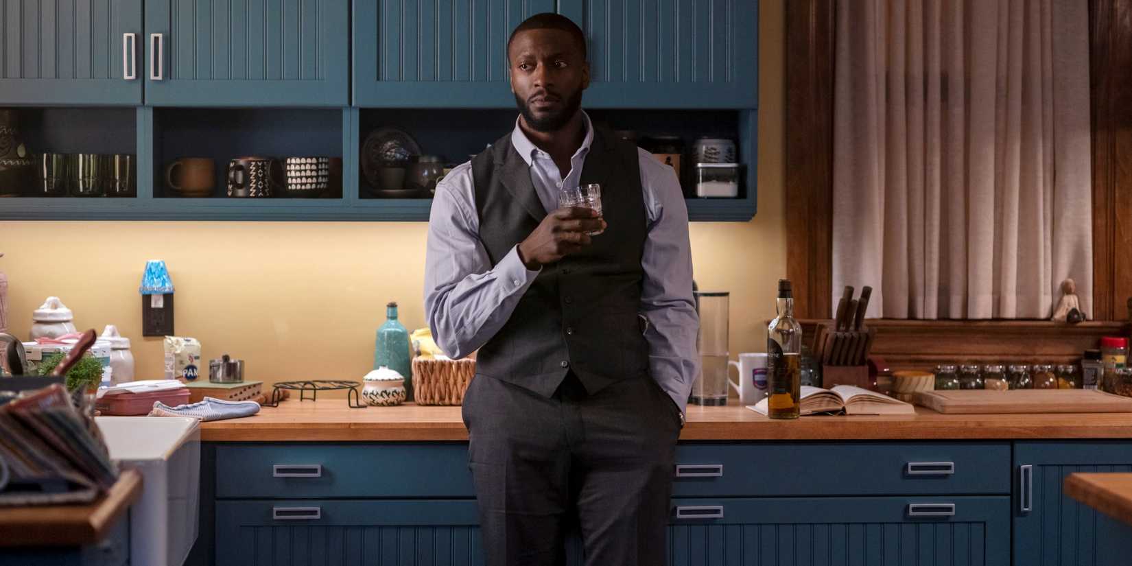 Aldis Hodge as Detective Alex Cross standing in the kitchen holding a glass of alcohol in Season 1 of Cross