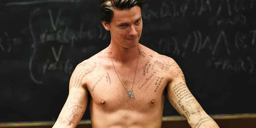 Daniel, played by actor Patrick Schwarzenegger, stands at the front of a classroom, shirtless and with his arms outstretched, with writing and diagrams all over his torso, in Daniel Isn't Real.
