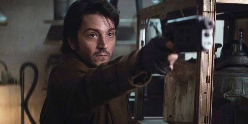 Diego Luna as Cassian Andor pointing a gun at someone off-camera in Andor.