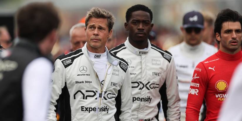 Brad Pitt and Damson Idris in racing outfits walking with others in F1.