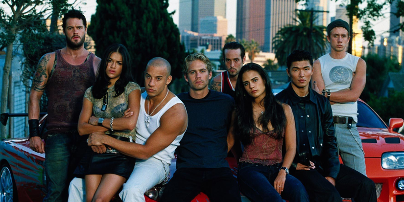 The cast pose in front of colorful sports cars with a city behind in The Fast and the Furious, 2001.