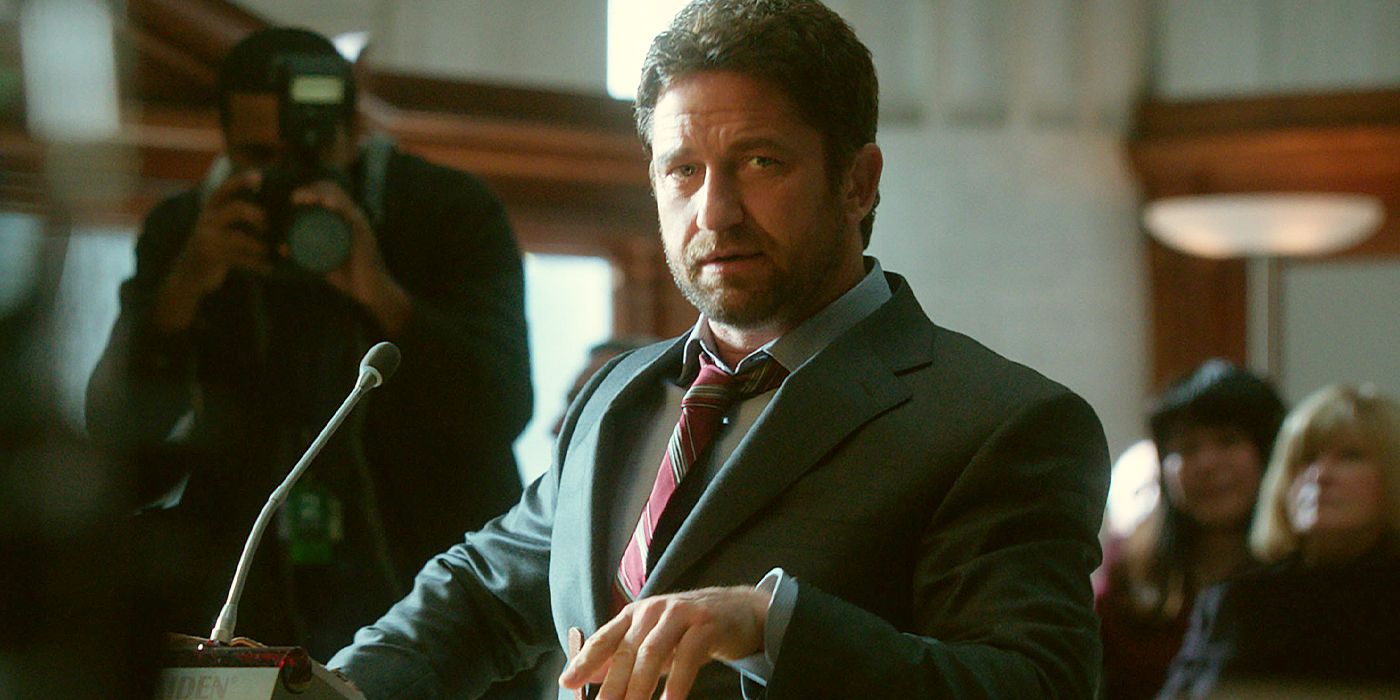 Gerard Butler speaking a podium in a courtroom in Geostorm