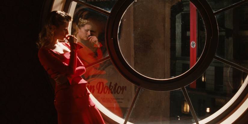 A woman in a red dress looks contemplative next to a large circular window in Inglourious Basterds.