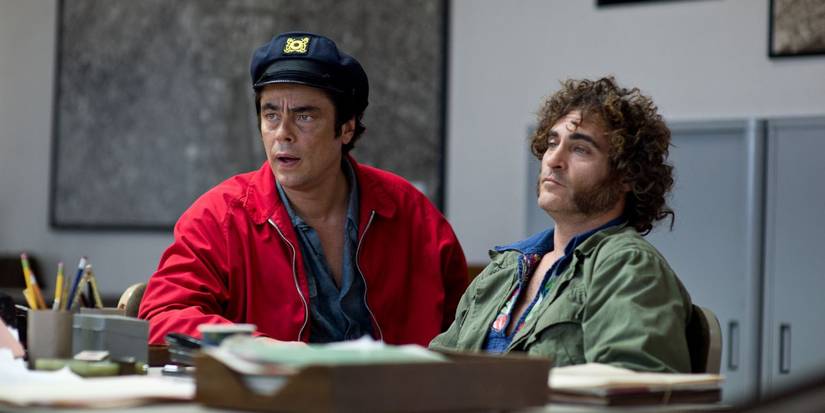 Benicio del Toro and Joaquin Phoenix sit at a desk and look disheveled in 'Inherent Vice'.