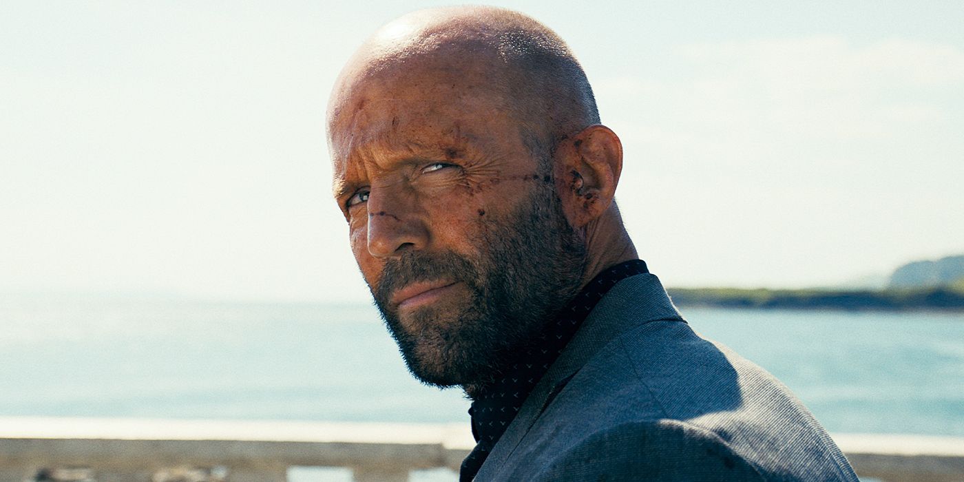 Jason Statham as Adam Clay with a bloodied face looks up with a slight smile in The Beekeeper