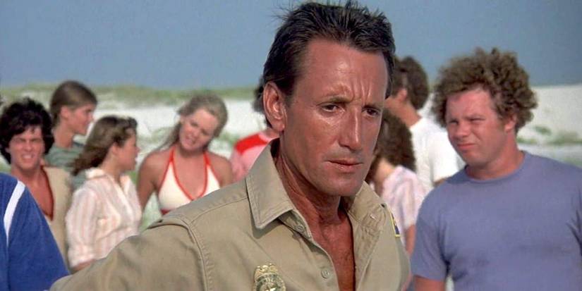 Roy Scheider as Chief Brody looking out at water with beachgoers behind him in Jaws 2.