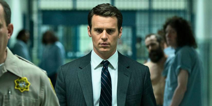 Jonathan Groff in a suit and a tie walking in a prison in Mindhunter.