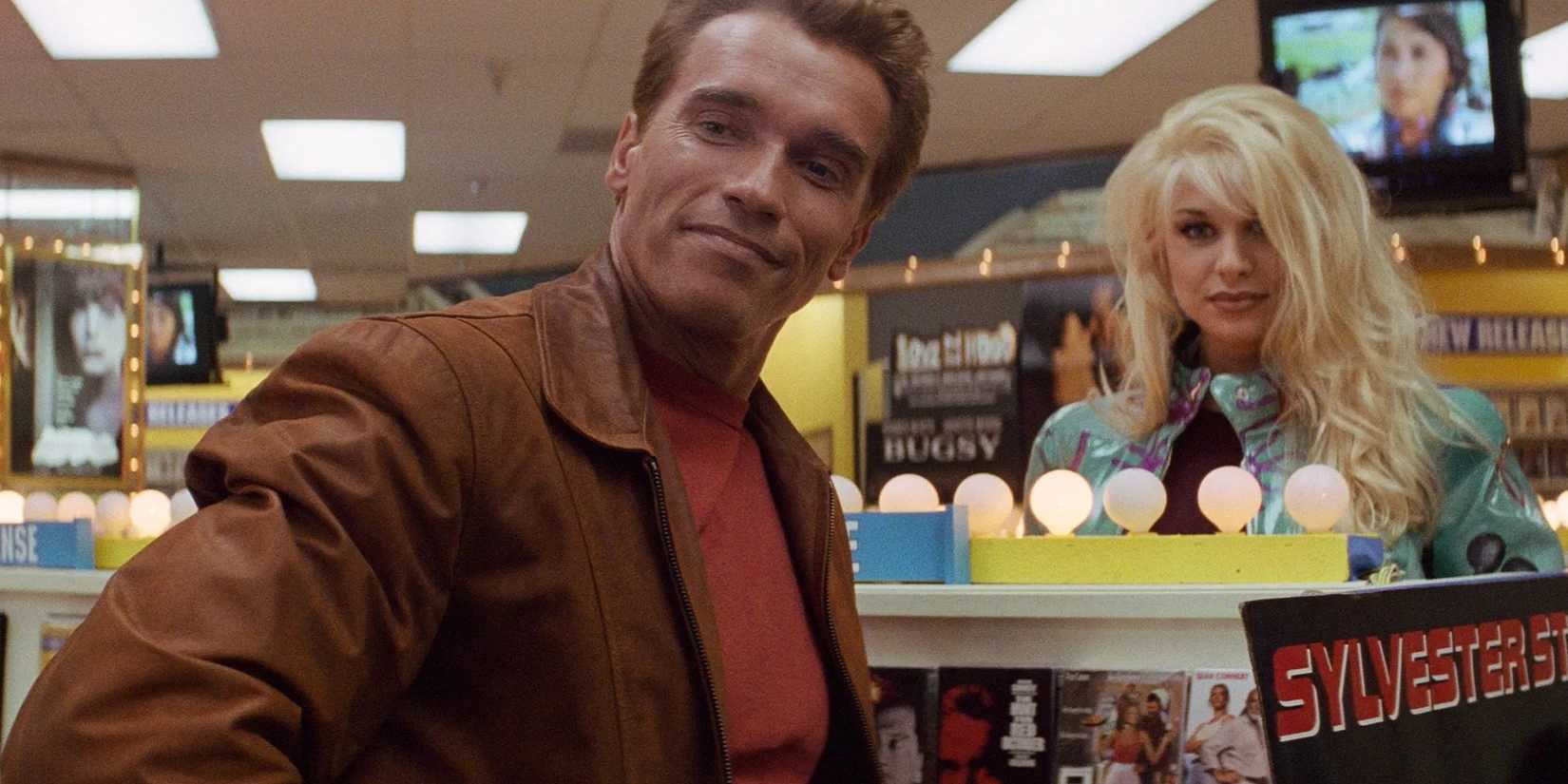 Jack Slater, played by actor Arnold Schwarzenegger, stands smiling next to a blond woman in a video store in Last Action Hero.